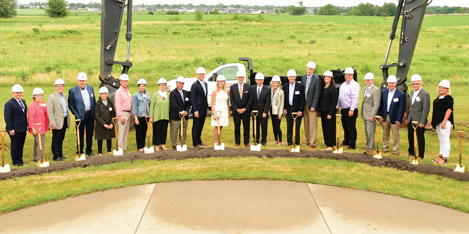 A group of buisiness people with hard hats and shovels at a worksite